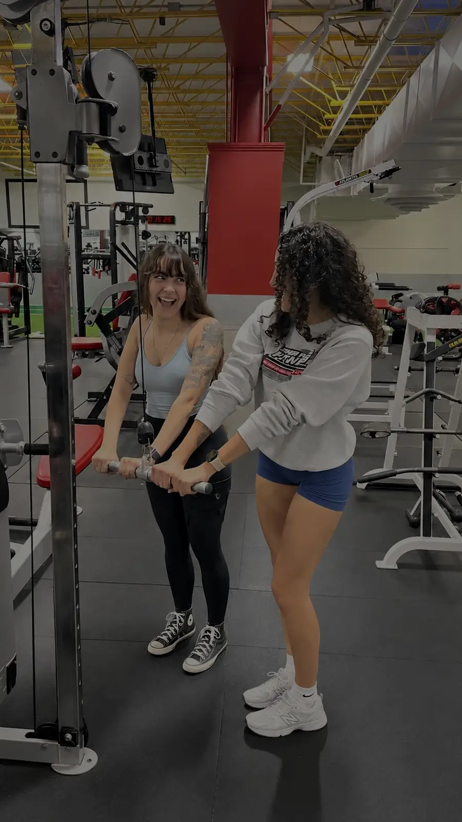 Two friends laughing together while training on the cable machine at Super Future Fitness