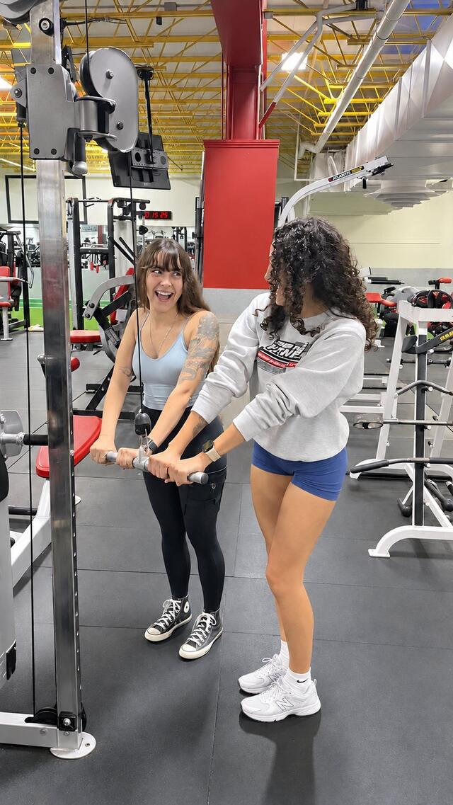 Two friends laughing together while training on the cable machine at Super Future Fitness