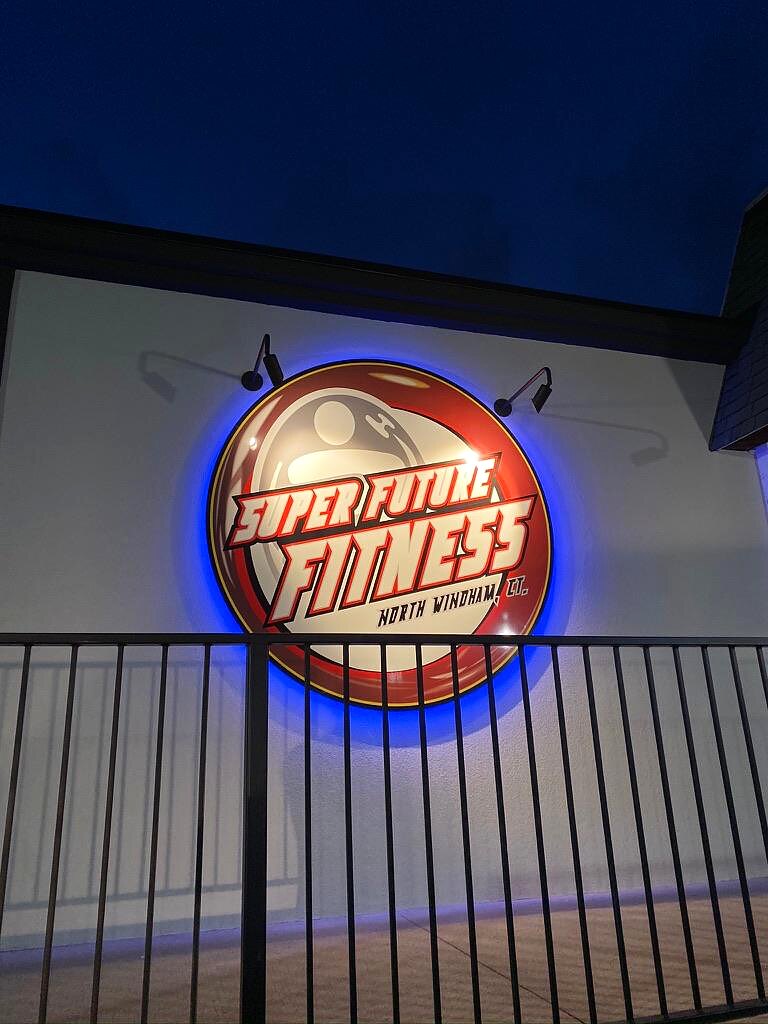 Round Super Future Fitness sign lit up at night on the side of the building