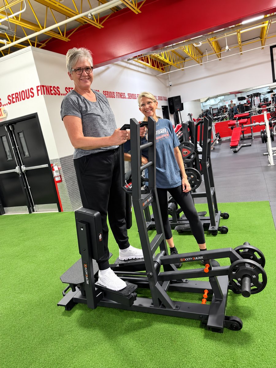 Two women smiling while training on Booty Builder machines