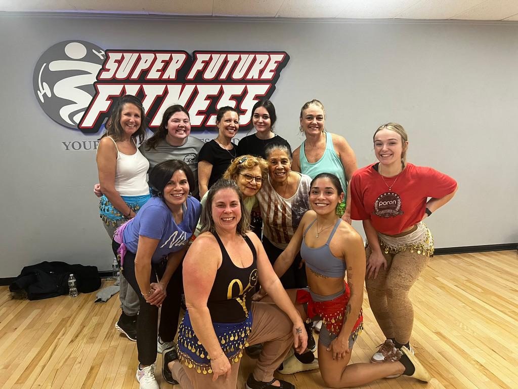 Zumba class group photo in front of the Super Future Fitness logo